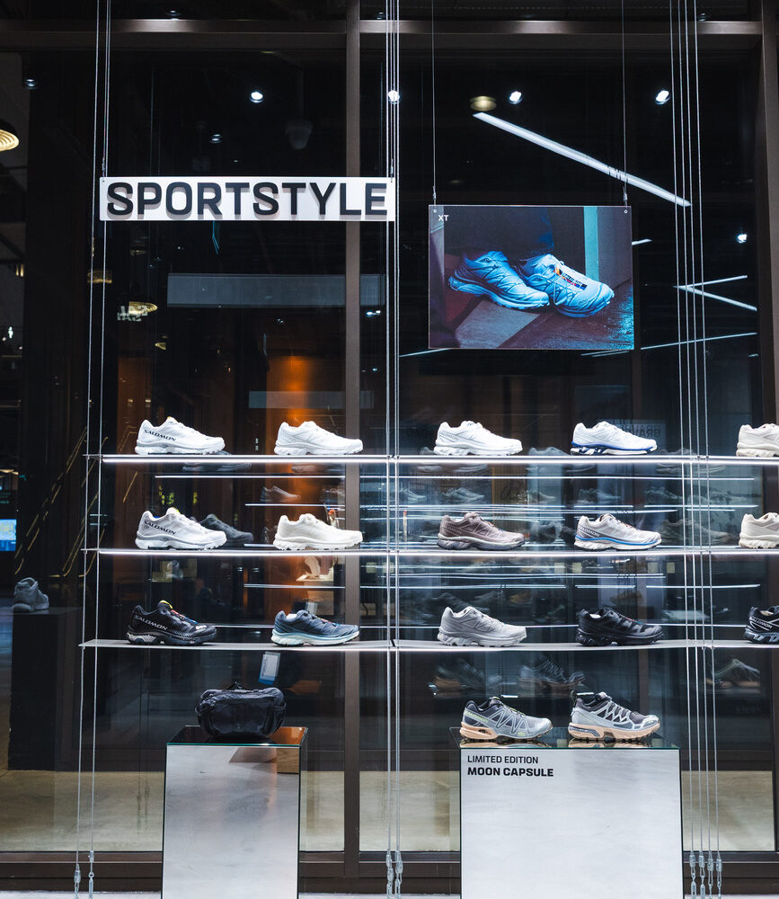 Salomon Battersea shoes displayed on window-facing shelves, illuminated by Zeplinn retail lighting.