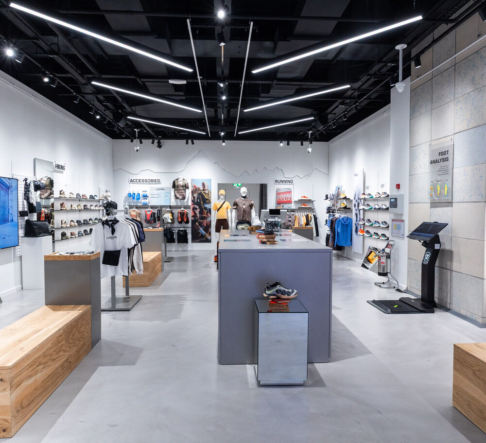 Interior view of Salomon Battersea store, showing layered architectural lighting and product displays.