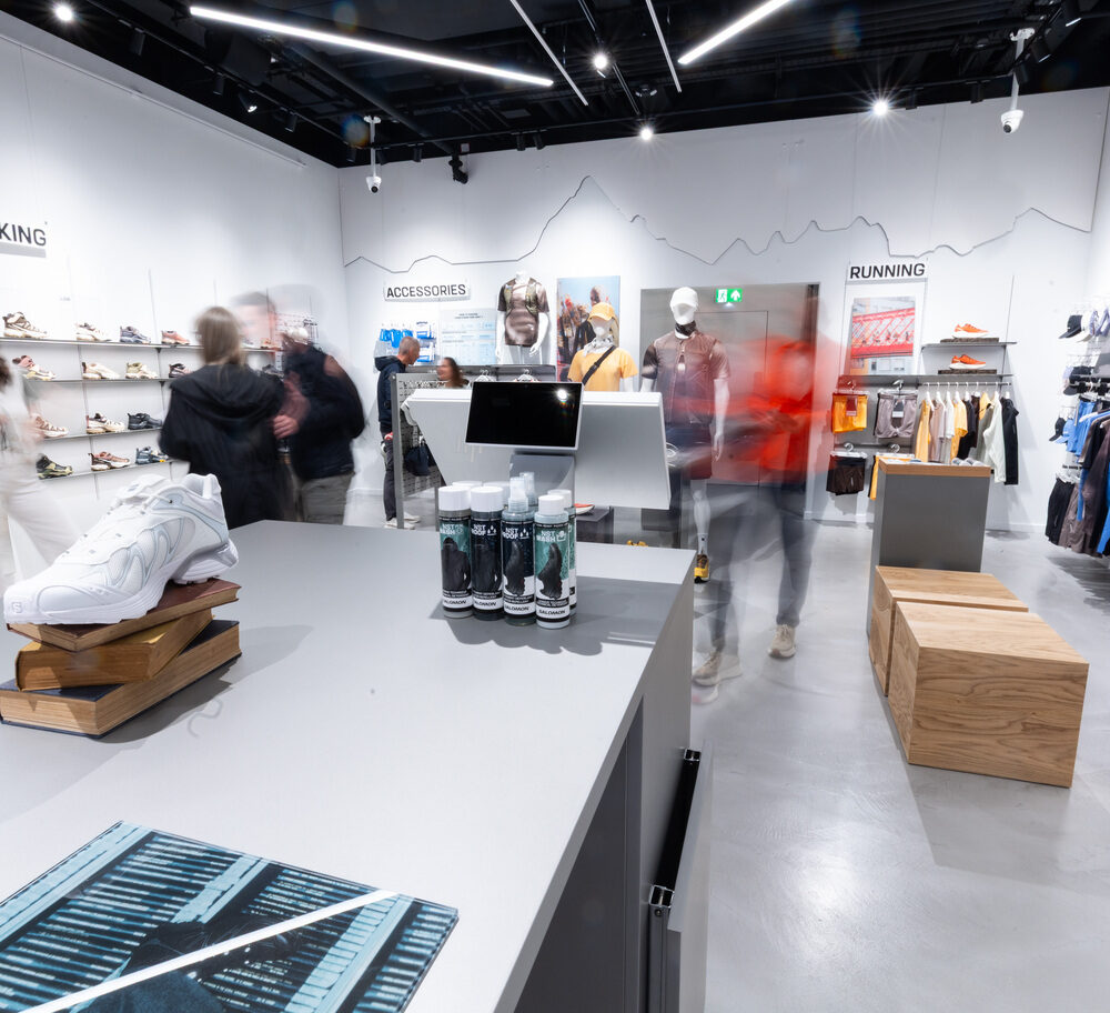 View from behind a central display table in Salomon Battersea store, illuminated by Zeplinn lighting.